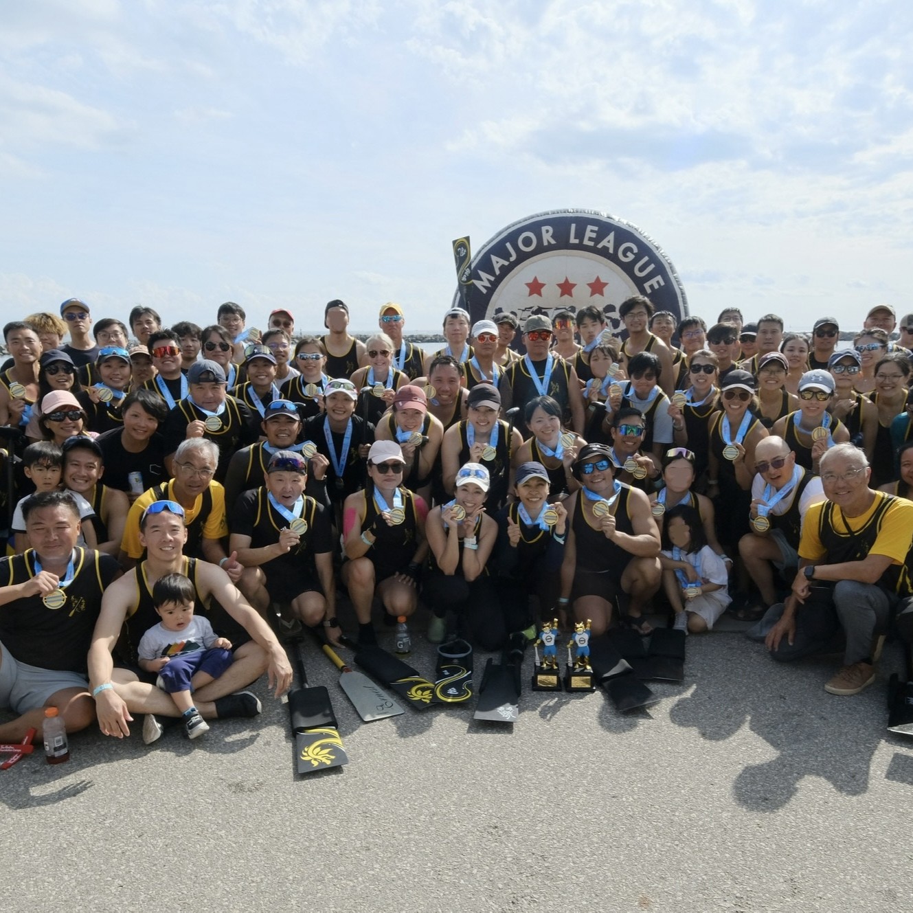 TOHK team celebrating with medals in front of the Major League sign